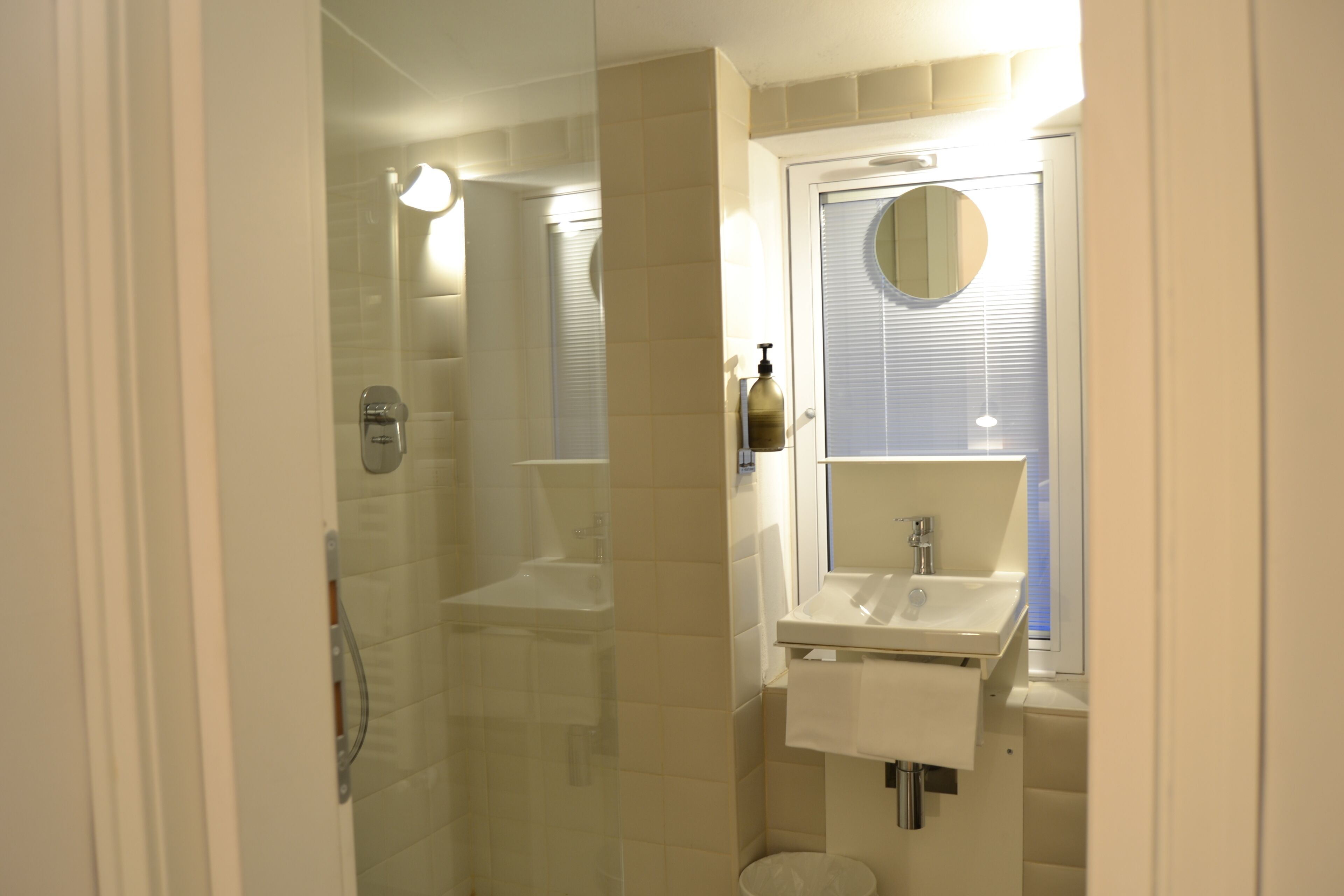 A bathroom with a glass-enclosed shower, a sink, and a mirror.