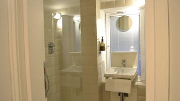 A bathroom with a glass-enclosed shower, a sink, and a mirror.