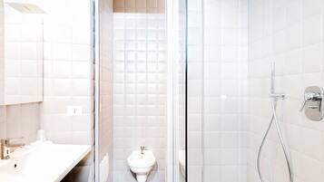 Ein modernes Badezimmer mit einem weißen Waschbecken, einem Bidet und einer Dusche.