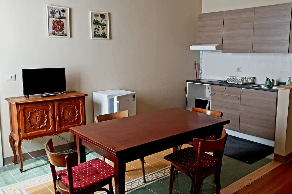 Een kleine keuken met houten kastjes, een eettafel en stoelen.