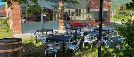 Un espace extérieur aménagé avec des tables et des chaises, un bâtiment en briques doté de fenêtres et une vue sur le paysage environnant.