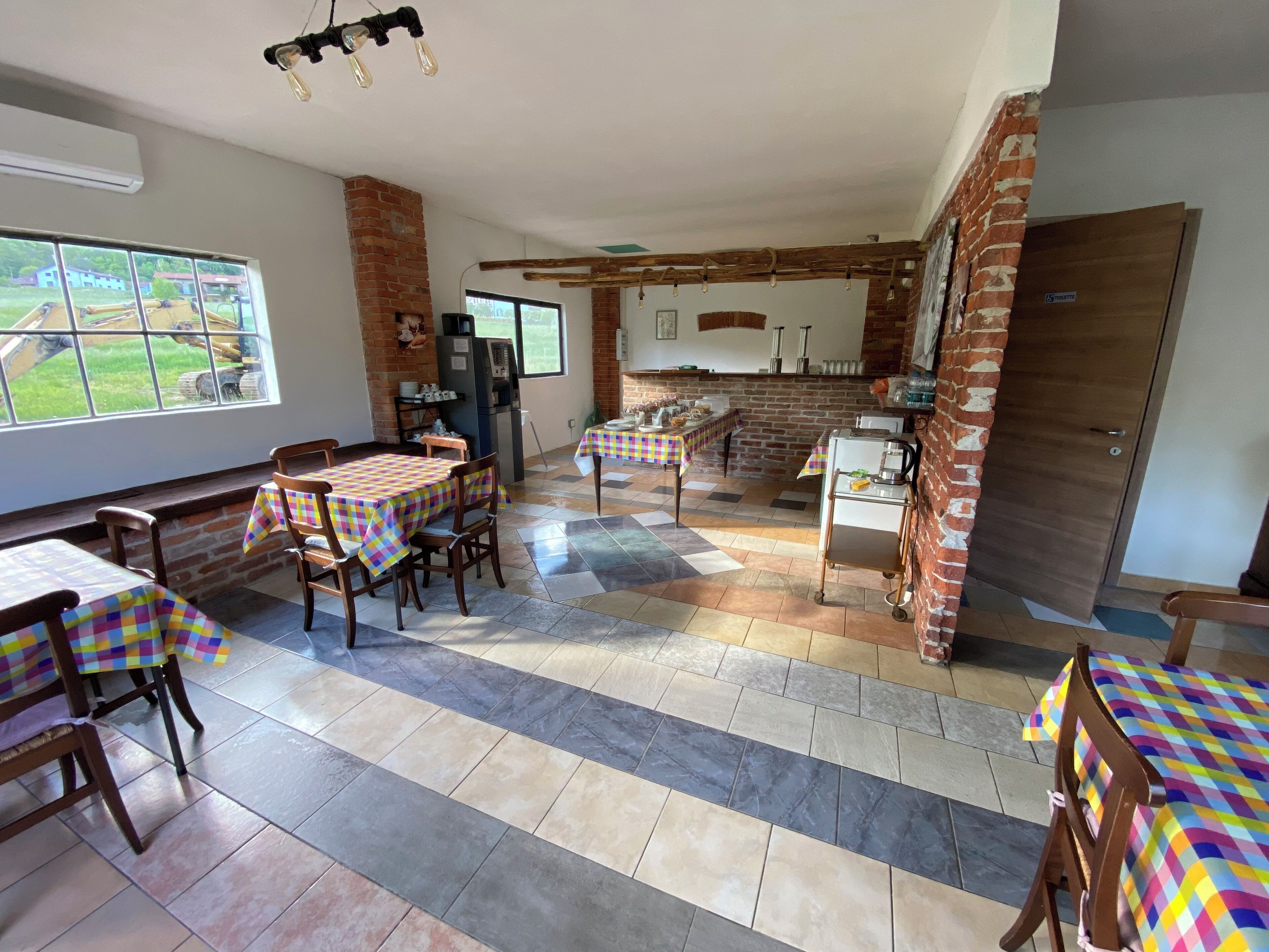 A dining area with checkered tablecloths, wooden chairs, and a brick wall.