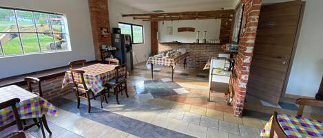 Un comedor con manteles a cuadros, sillas de madera y una pared de ladrillo.