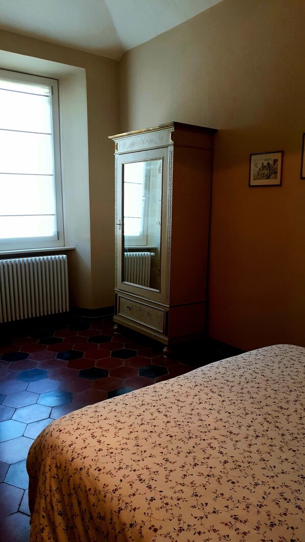 Una habitación con cama, radiador, ventana y armario.