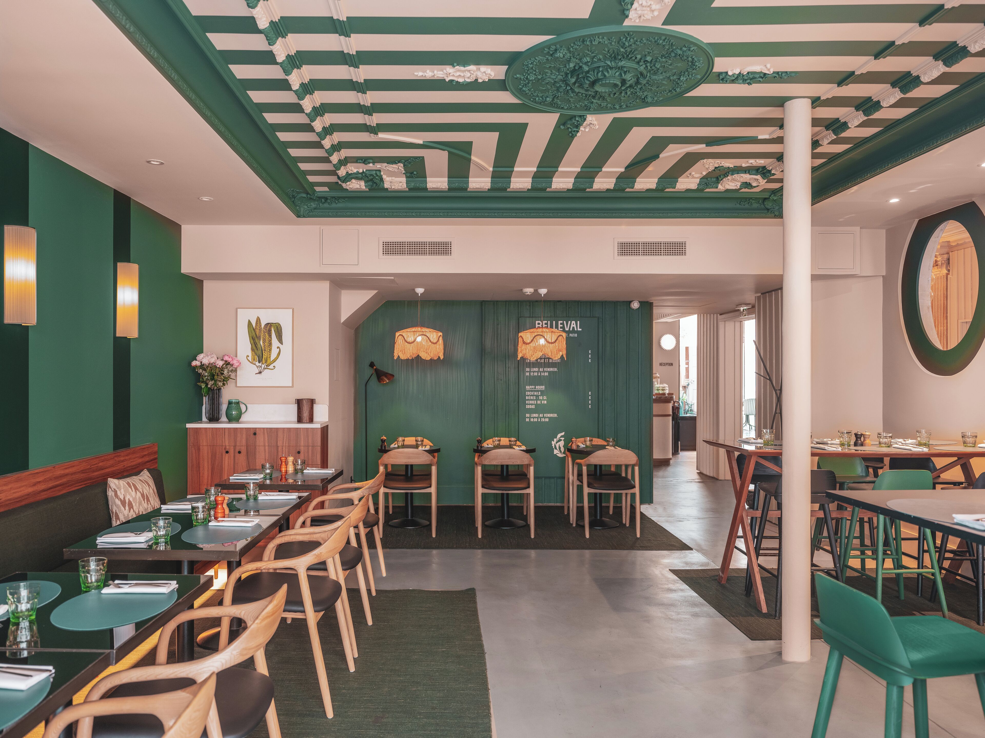 A restaurant with a green and white striped ceiling, wooden chairs, and tables.