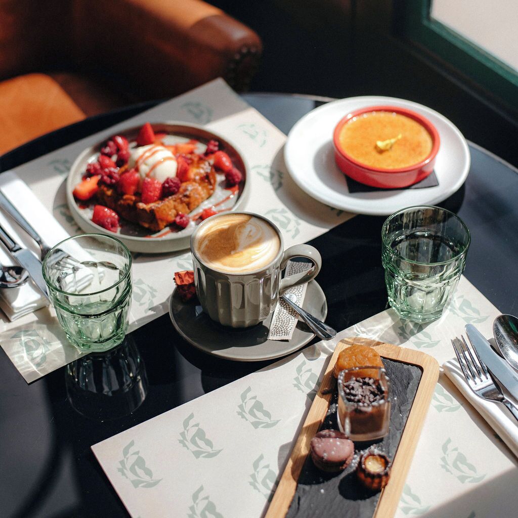 A table set with a dessert plate, a bowl of soup, a cup of coffee, and two glasses of water.