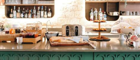 A breakfast bar with various food items, a toaster, and a display of pastries.