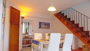 Ein Essbereich mit Tisch und Stühlen, eine Treppe und ein Bücherregal mit Büchern.