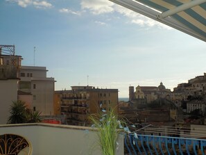 A cityscape with buildings, a clear sky, and a balcony with a railing.