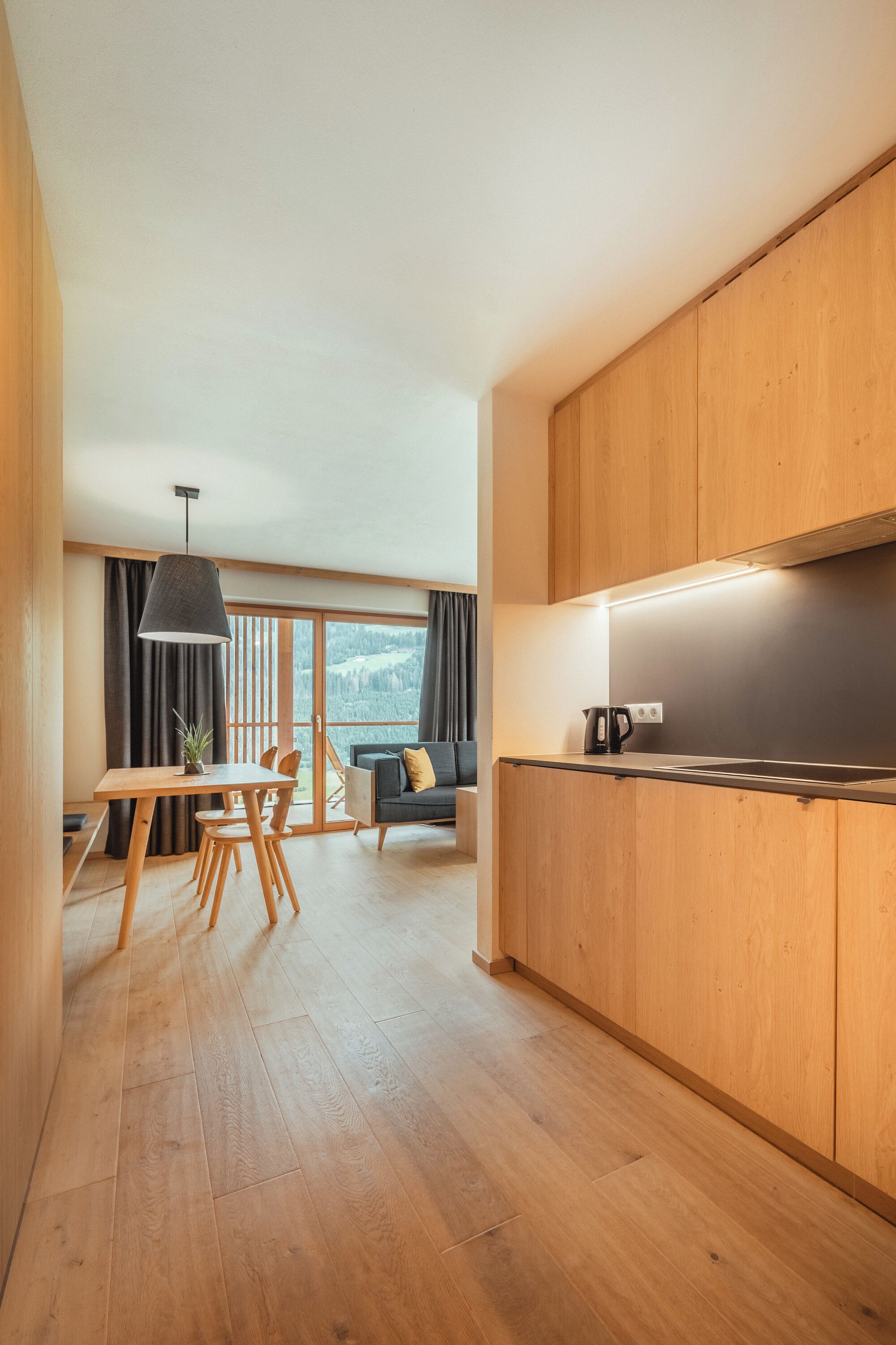 Una cucina moderna con mobili in legno, un'area pranzo con tavolo e sedie, e un divano.