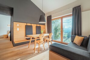 Un espacio habitable moderno con comedor, sofá y un amplio ventanal con vistas al exterior.