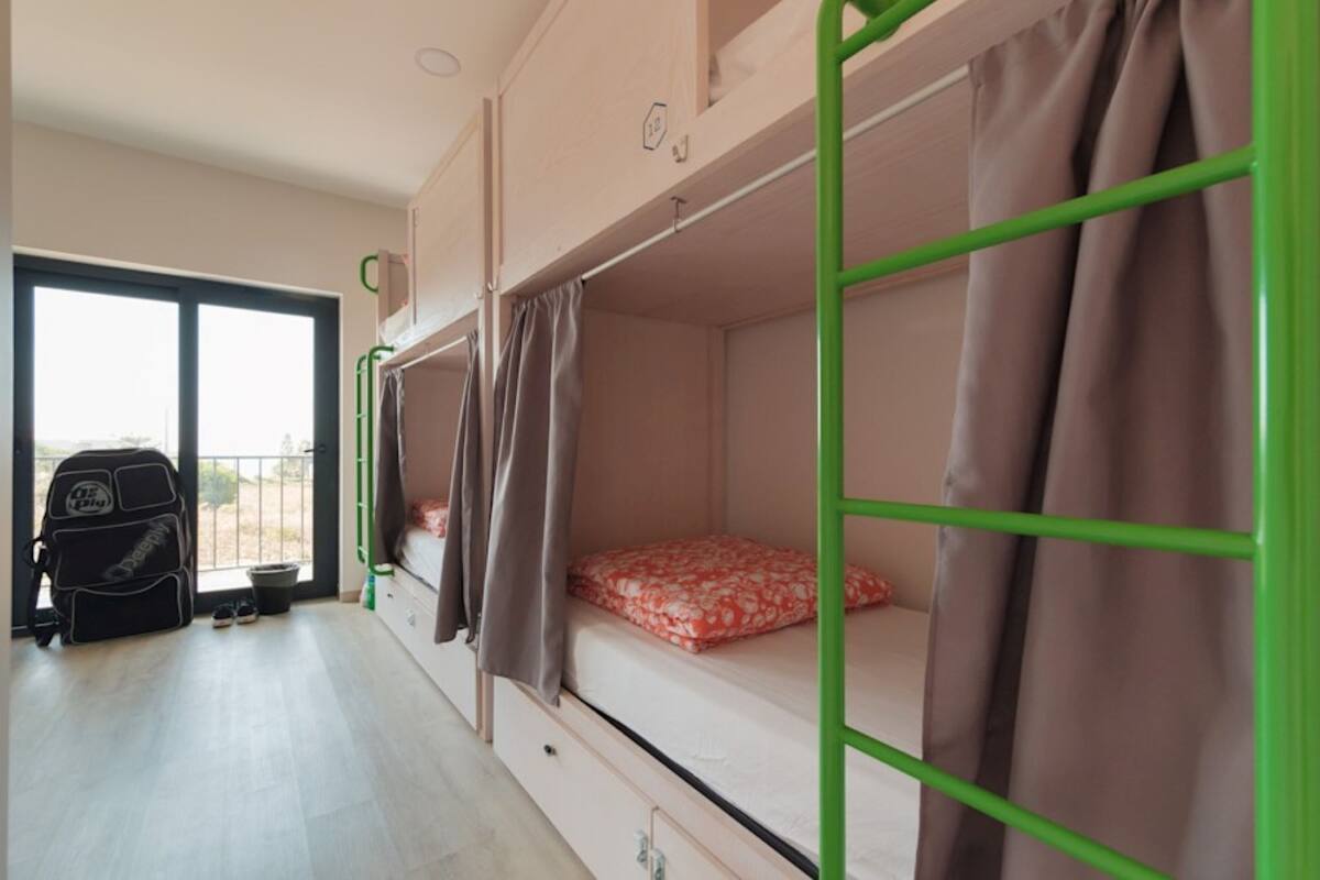 Un dormitorio con literas, una maleta y una ventana.