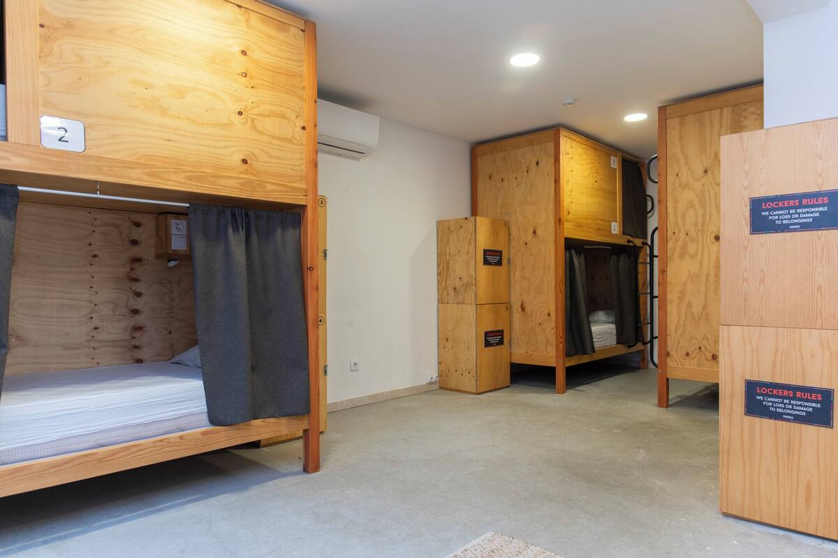 Una habitación con literas, taquillas de madera y un cartel con las normas de las taquillas.