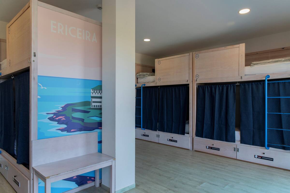 Una habitación con literas, una mesita pequeña y un muro con un mural colorido.