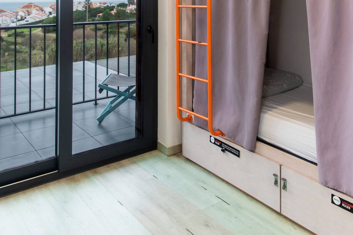 Una habitación con literas, un ventanal corredero que da a un balcón y vista al mar.