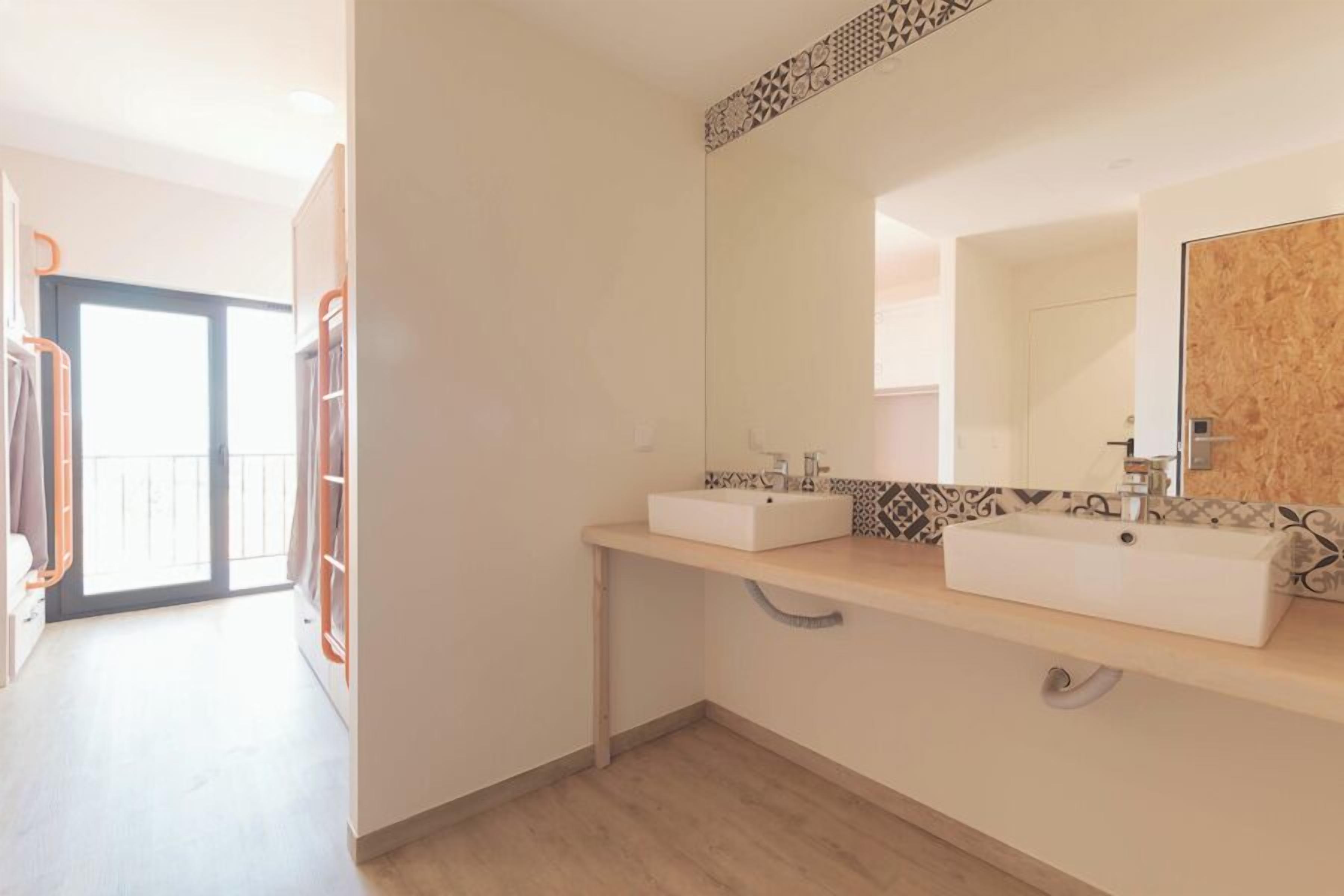 A modern bathroom with two sinks, a large mirror, and a patterned tile backsplash.