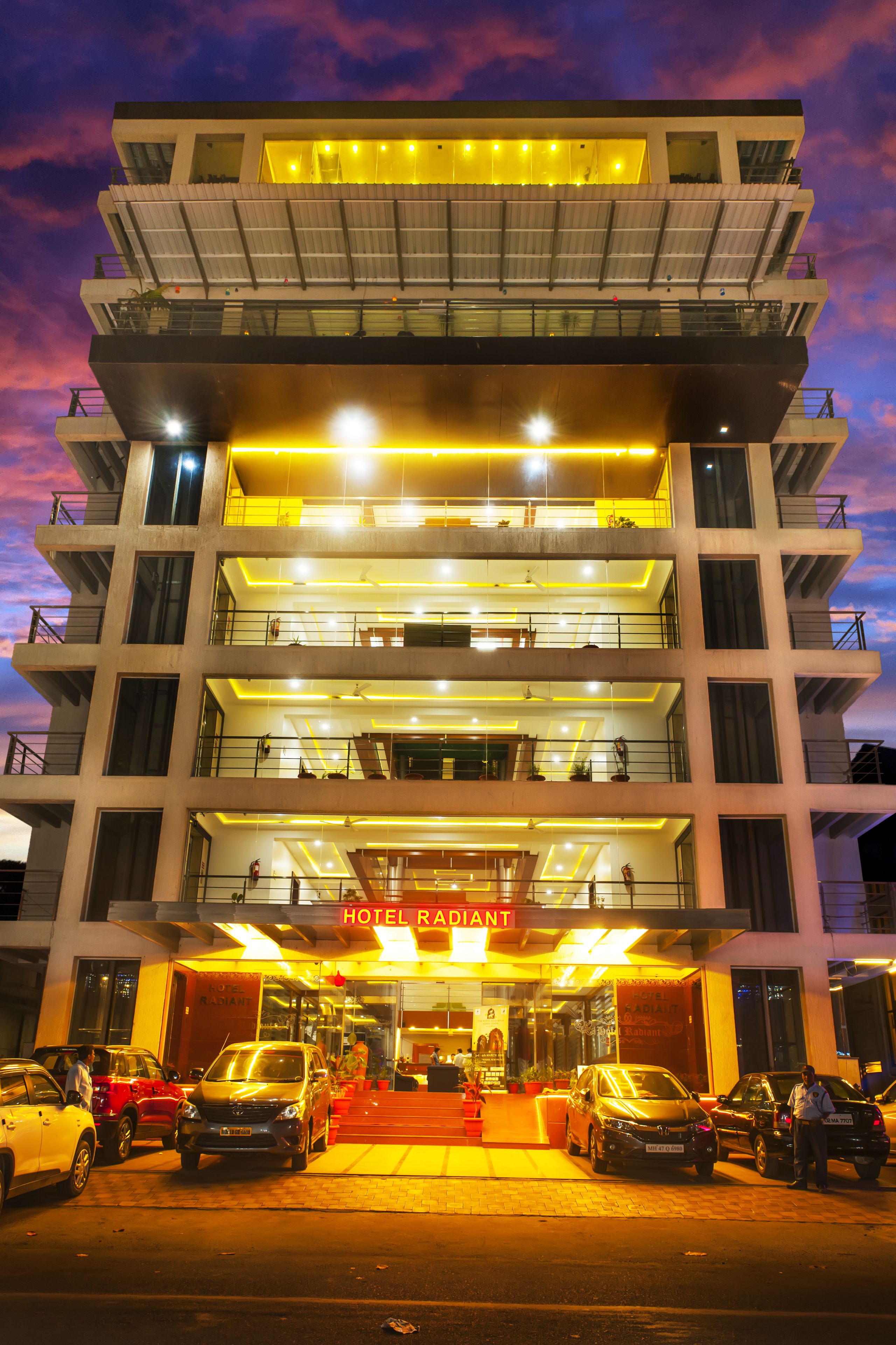 A multi-story hotel with a modern design, featuring balconies on each floor and a well-lit entrance.
