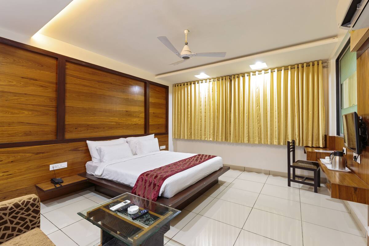 A hotel room with a bed, a desk, a chair, a coffee maker, and a telephone.