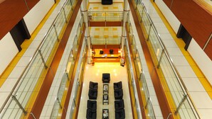 A multi-level atrium with a reception desk, seating area, and glass railings. - Hotel Radiant (Kolhapur)