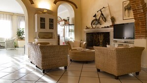 Uma sala de estar com móveis de vime, lareira, televisão e uma bicicleta pendurada na parede.