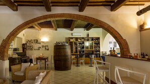 Um interior acolhedor com um arco de tijolos, uma adega, móveis de vime e um espaço de bar.