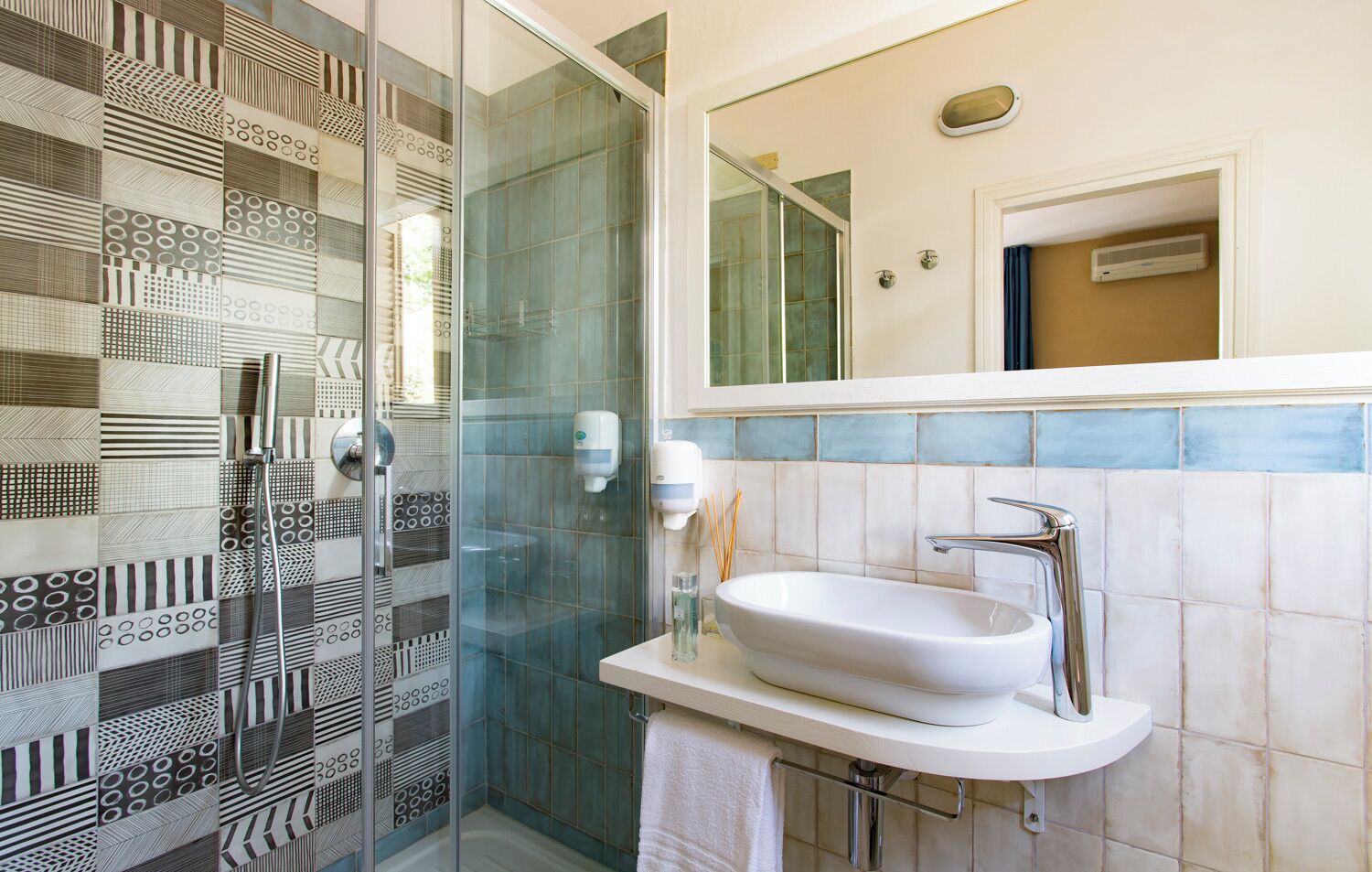 Un baño moderno con cabina de ducha de vidrio, un lavabo blanco con grifo cromado y un espejo sobre el lavabo.