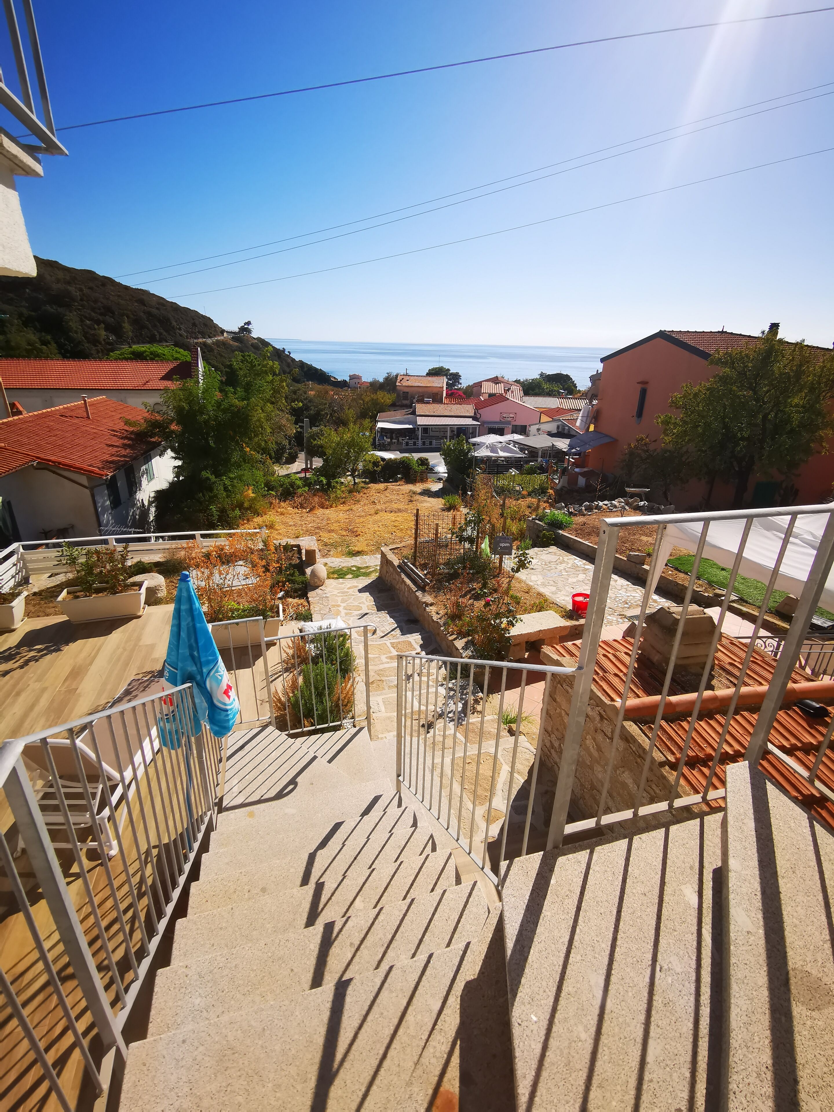A balcony with a view of a residential area, including houses and a hillside.