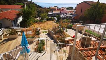 A balcony with a view of a residential area, including houses and a hillside.