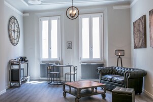 Ett vardagsrum med en soffa i läder, ett soffbord, en tv på ett tv-bord och ett element.