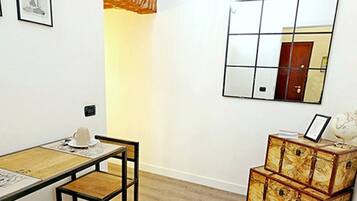 Une pièce avec un plancher en bois, une table à manger avec des chaises, un petit meuble contenant un globe terrestre et un miroir accroché au mur.