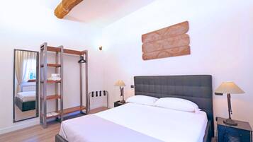 A hotel room with a large bed, two bedside tables, a wardrobe, and a mirror.