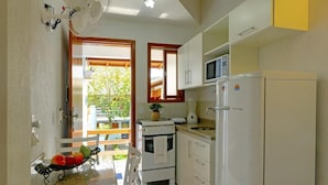 A compact kitchen with white appliances, a granite countertop, and a view through an open door. - Morada do Sol Apart Hotel Garopaba (Garopaba)