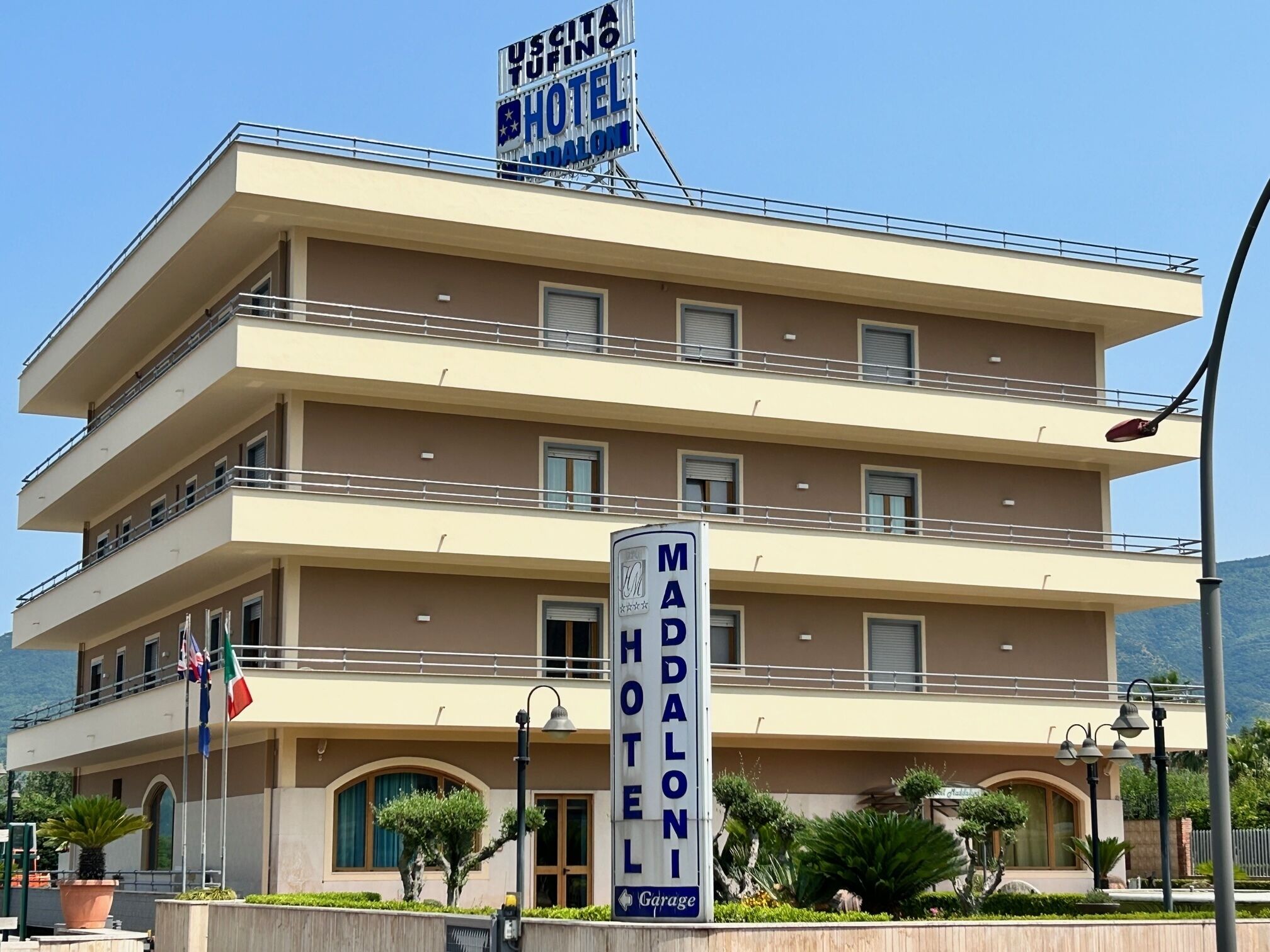 Un hotel de varios pisos con un cartel que dice 'Uscita Tufino Hotel' y 'Madalon Hotel'.