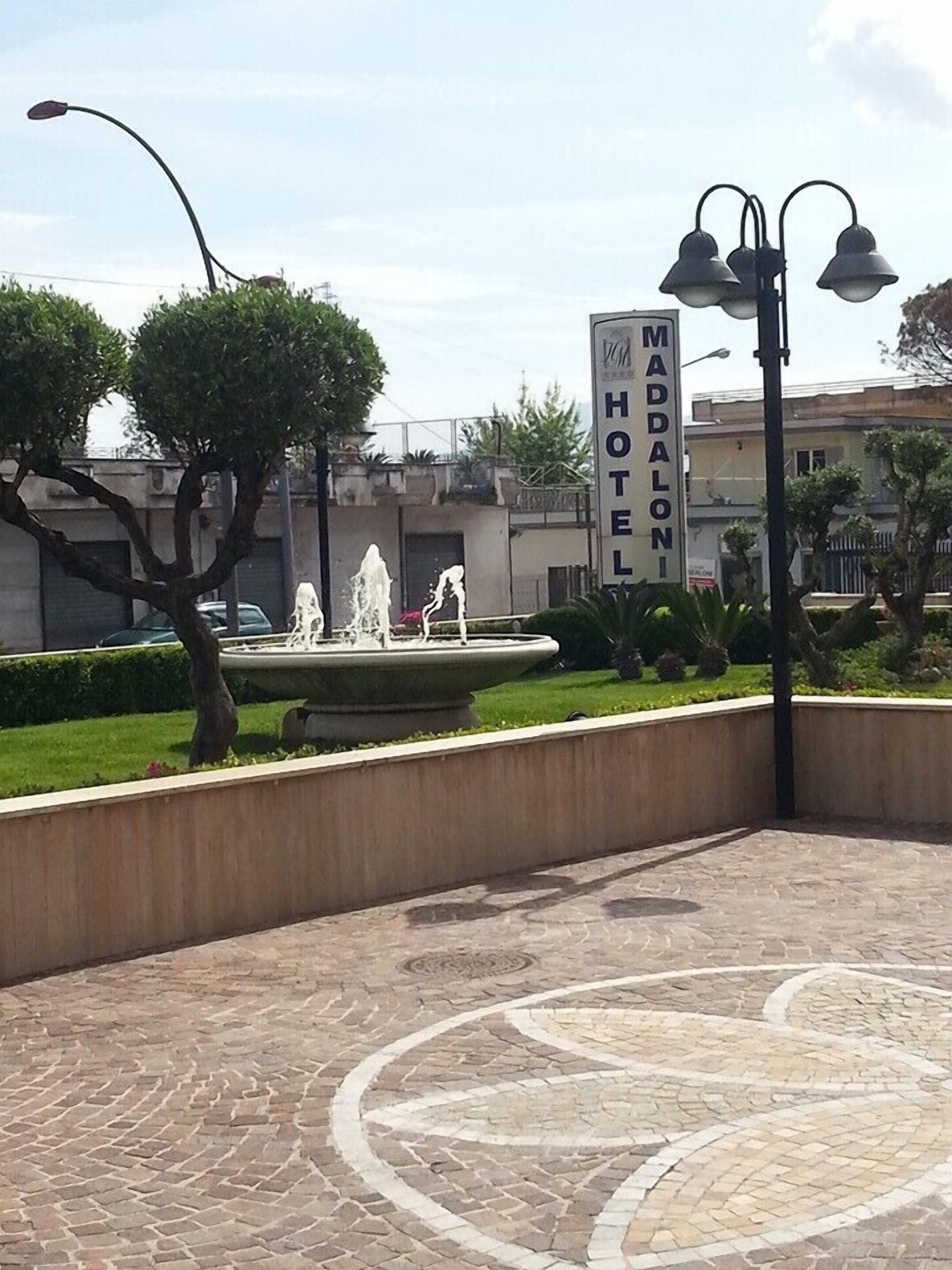 Ein Hotelschild mit einem Brunnen im Vordergrund.