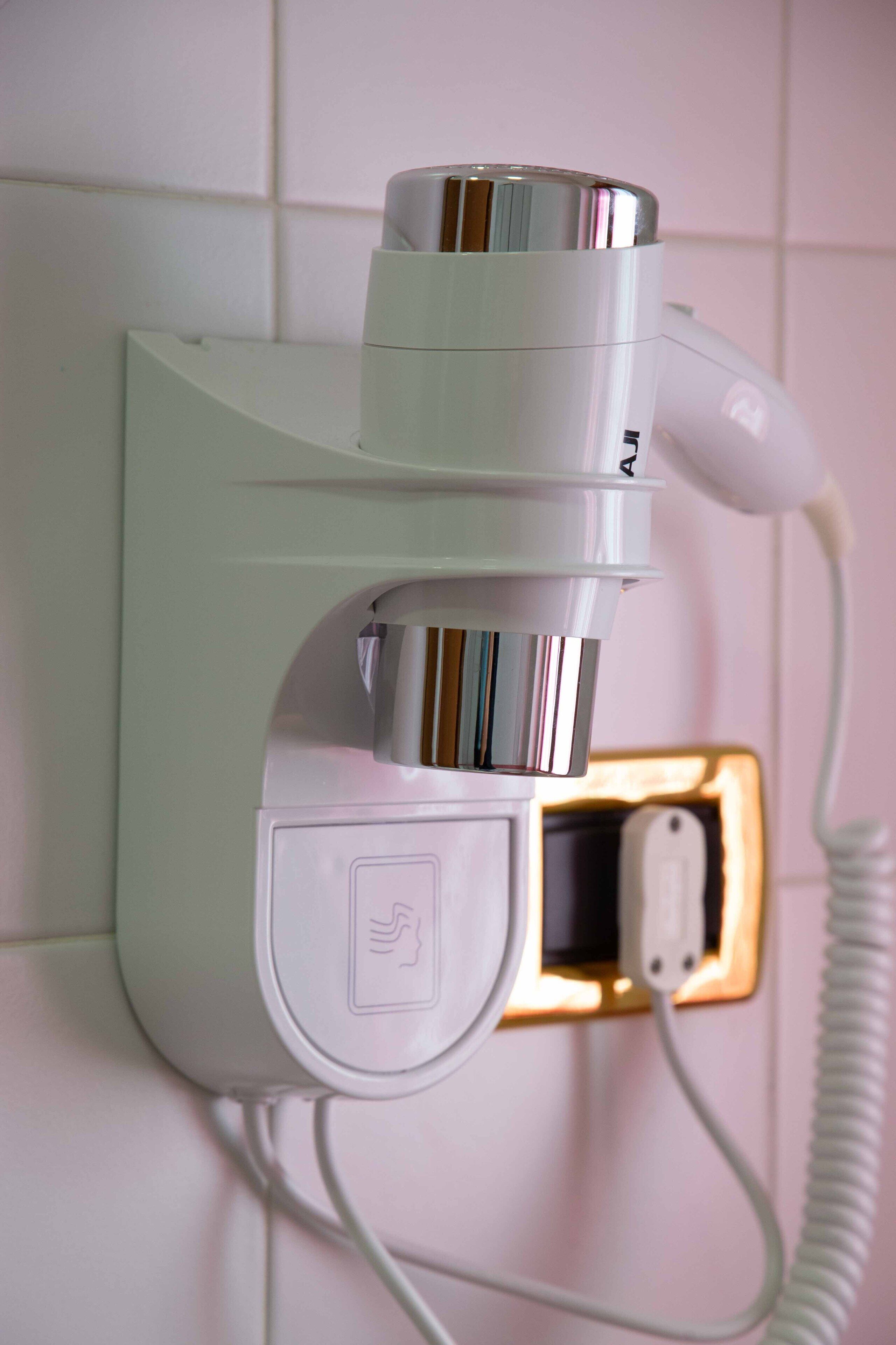 A hair dryer mounted on a wall with a power outlet and a USB port.