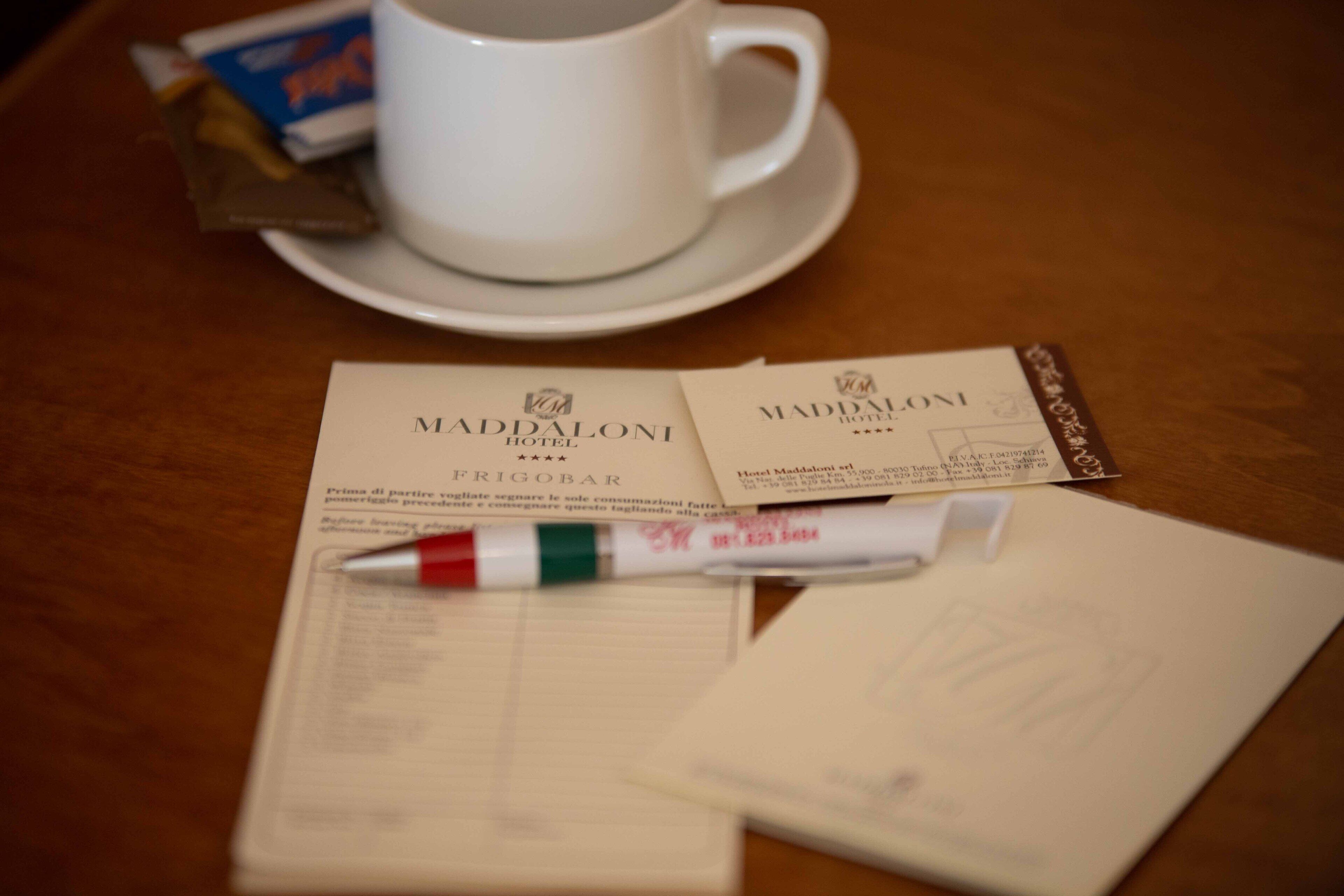 A hotel receipt, a pen, and a cup on a table.