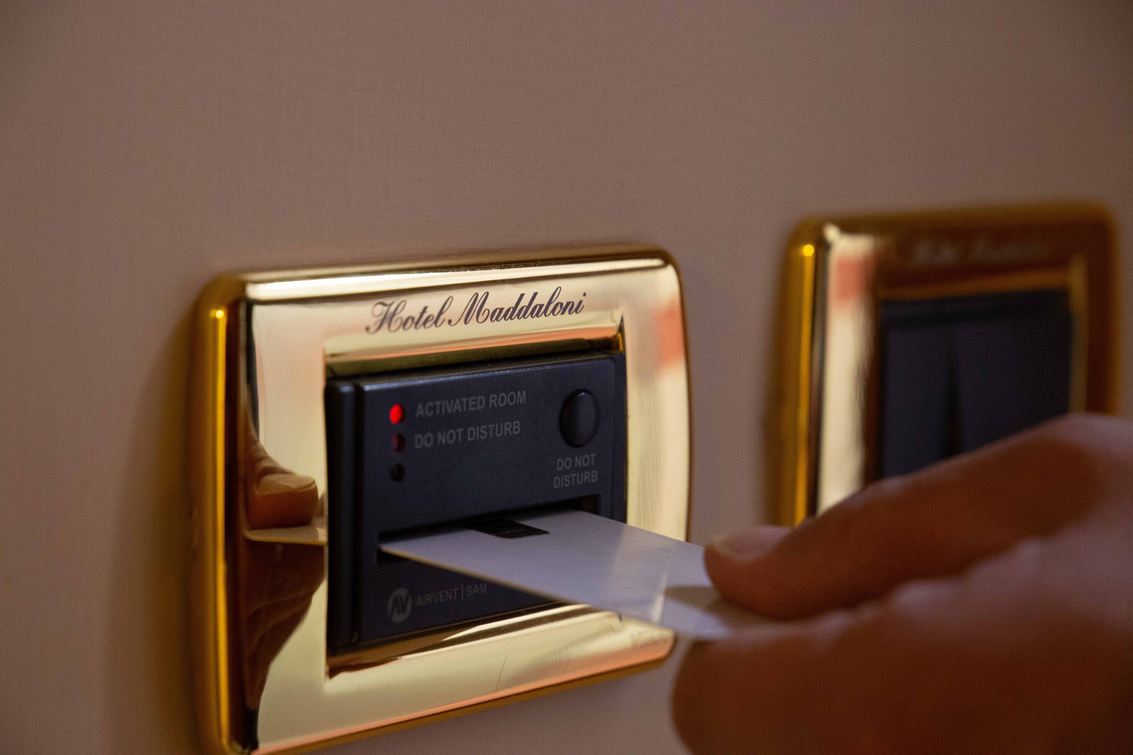 A hotel room's electronic keycard reader with a gold frame and a sign that reads "Hotel Maddaloni."