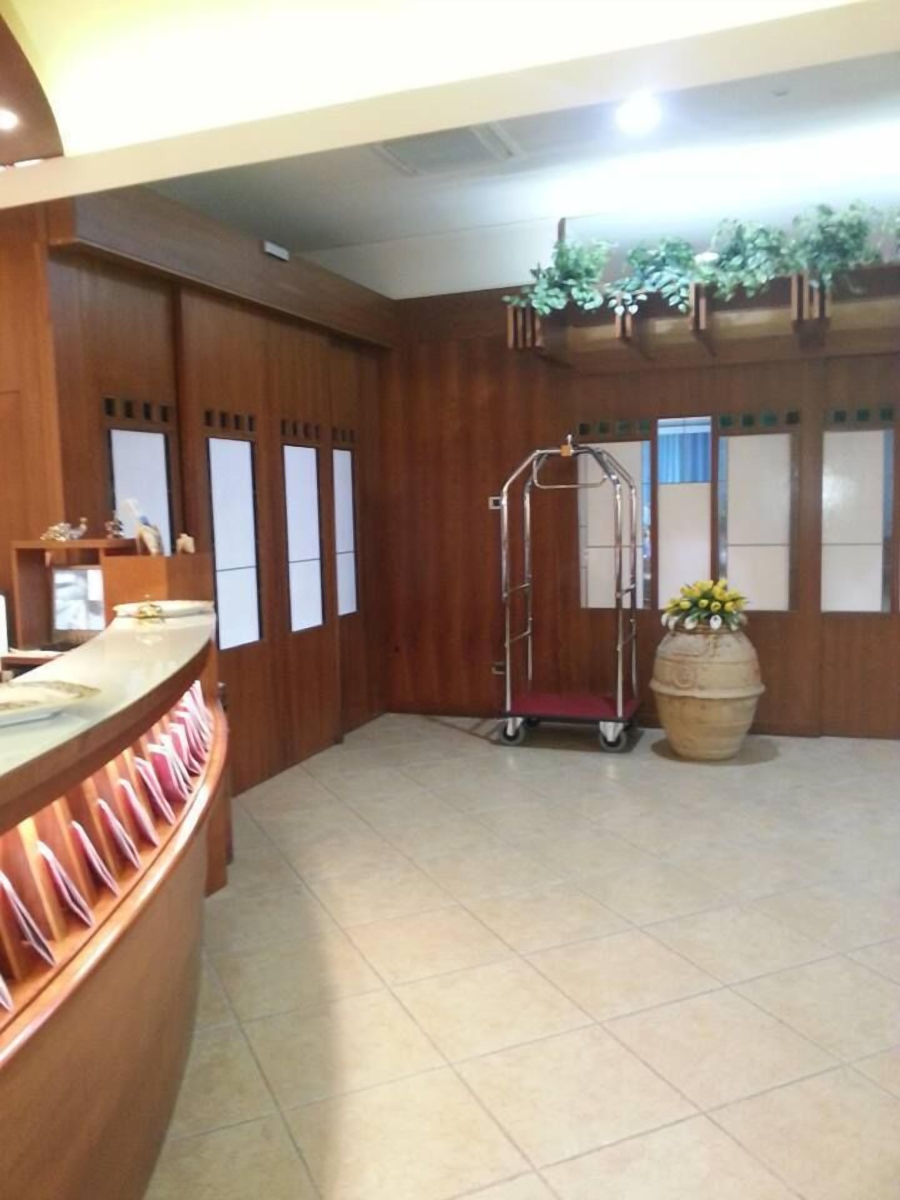 A reception area with a wooden counter, a metal cart, and a large potted plant.