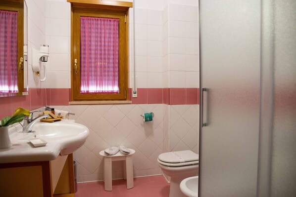 Een badkamer met een wastafel, toilet en een klein krukje.
