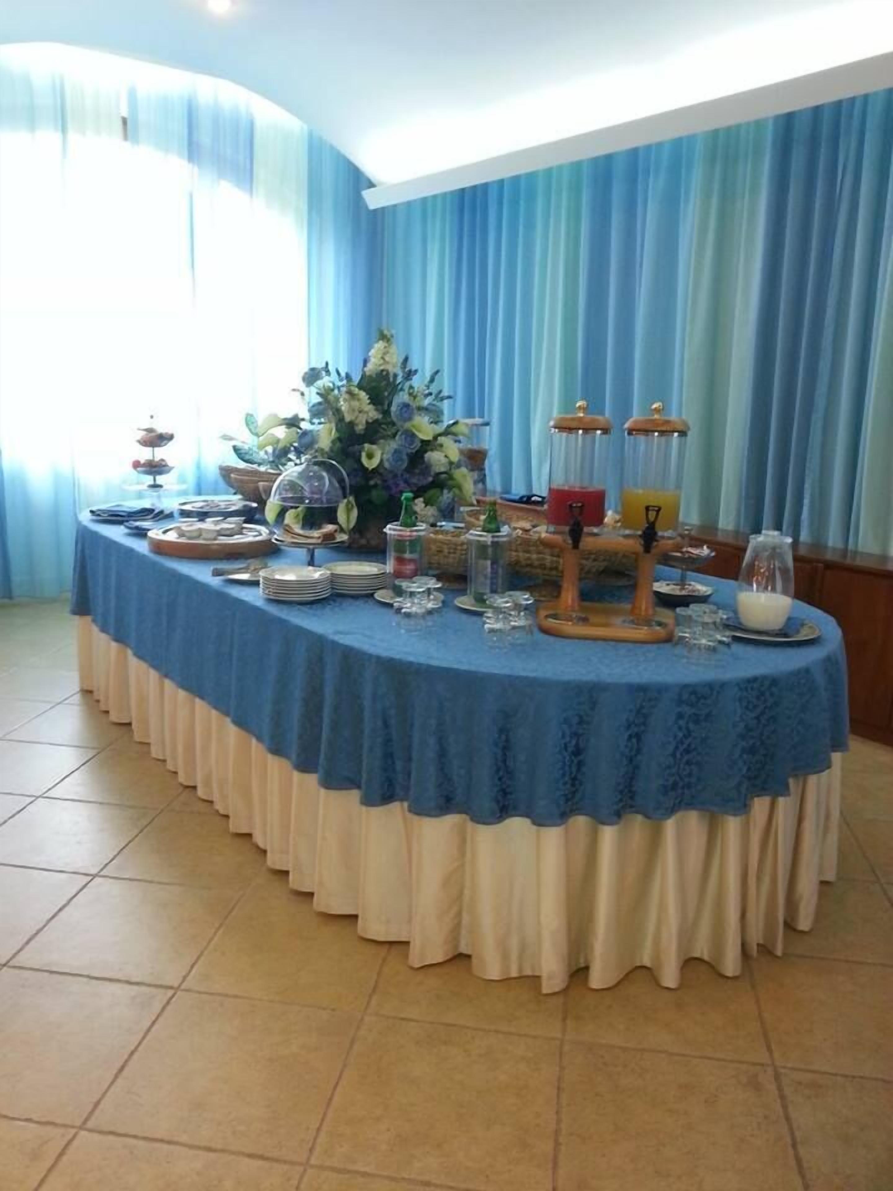 Una mesa de buffet con mantel azul, diferentes opciones de comida y un centro de mesa floral.