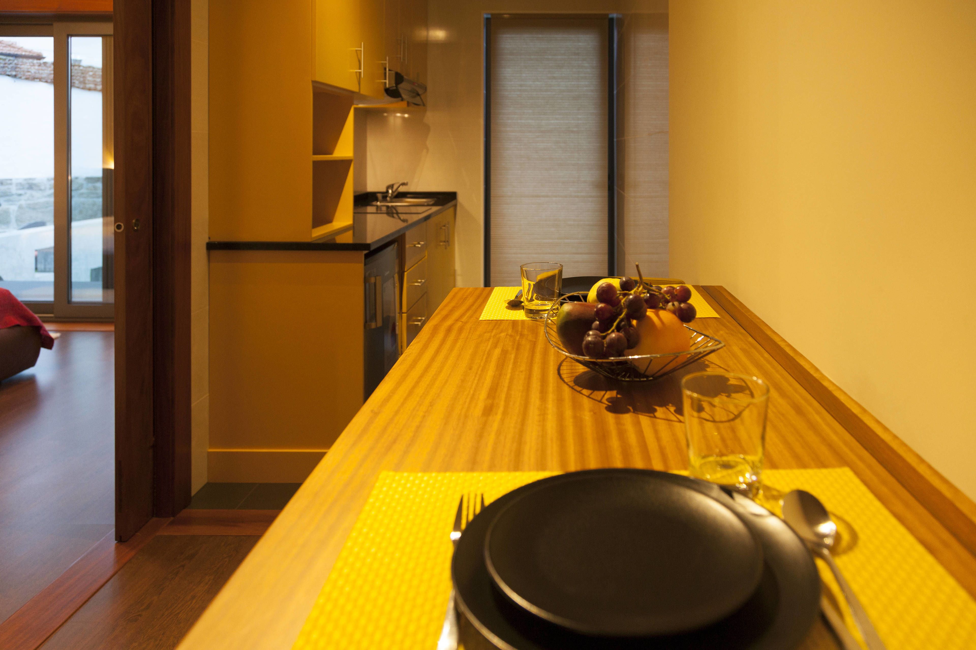 A dining area with a table set for two, a bowl of fruit, and a glass of water.