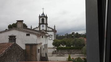 A church with a bell tower and a cross, surrounded by buildings and greenery.