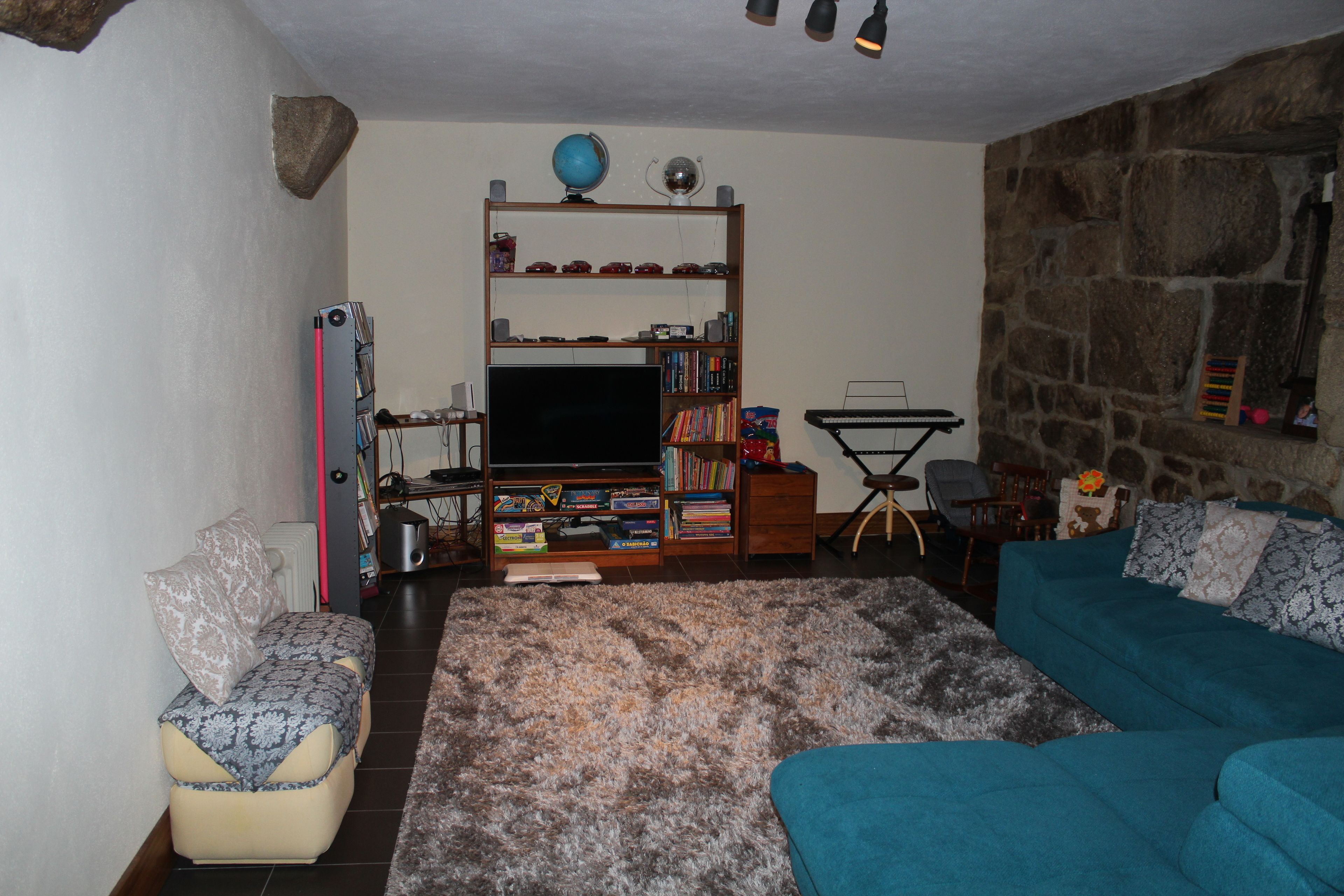 A living room with a sofa, a coffee table, a bookshelf, a television, and a stone wall.