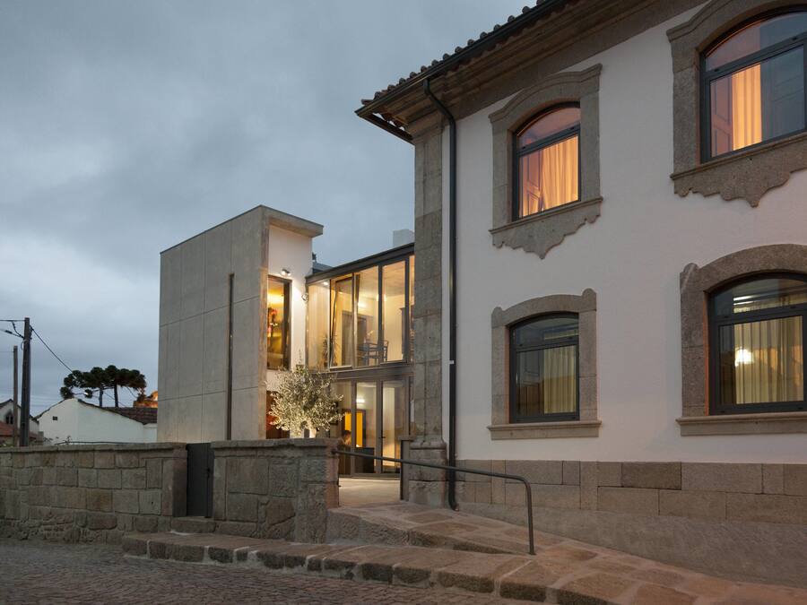 Un edificio con fachada de piedra, varias ventanas y una escalera que lleva a la entrada.