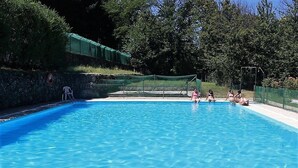Una piscina azul cristalina con un trampolín y un cartel de seguridad en la pared.