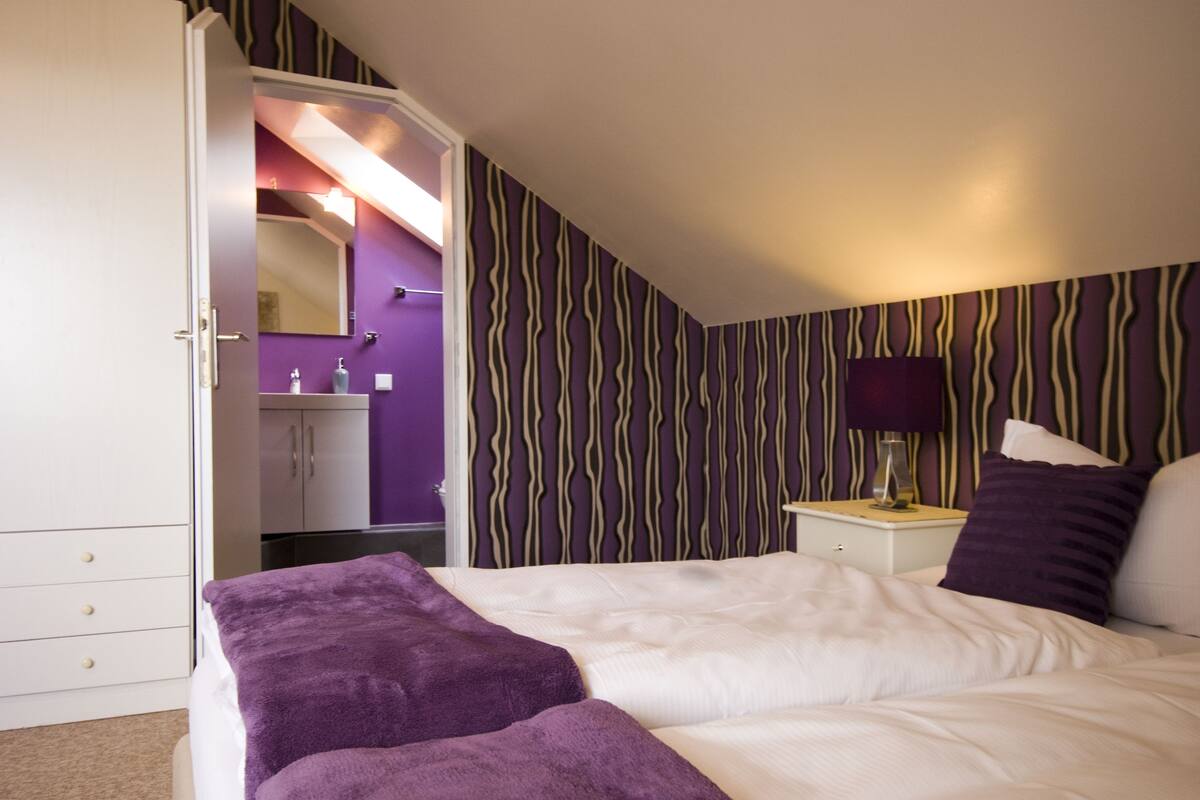 A bedroom with a bed, a nightstand, a mirror, and a wardrobe.