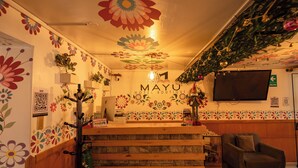 A reception area with a wooden desk, a grey armchair, and a wall with floral patterns. - Mayu Boutique Hotel (Cusco)