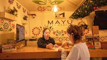 Mostrador de recepción en Mayu Hotel Boutique con diseño de pared floral, una lámpara colgante y una decoración navideña.