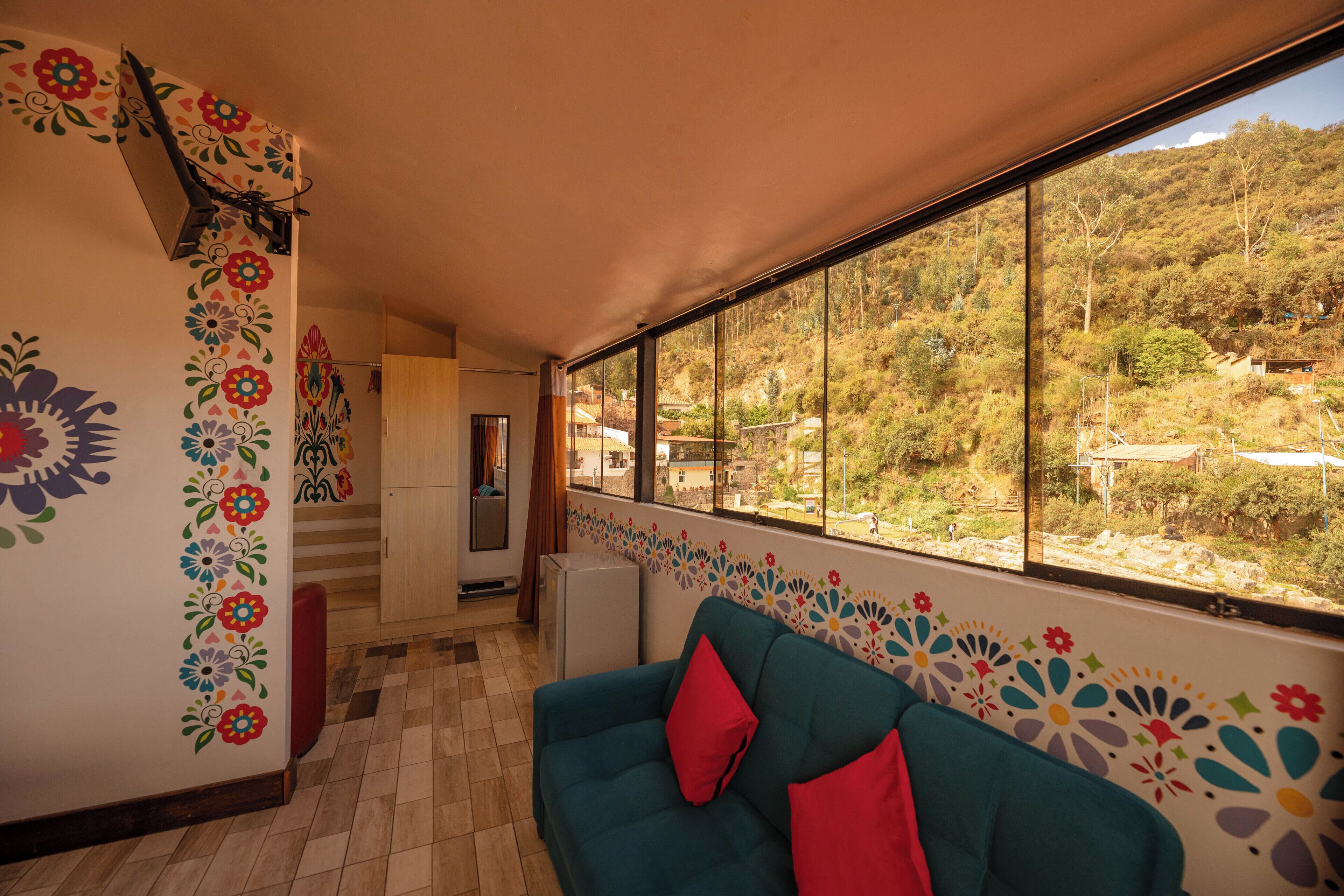 Una habitación con un ventanal grande, un sofá y un refrigerador.