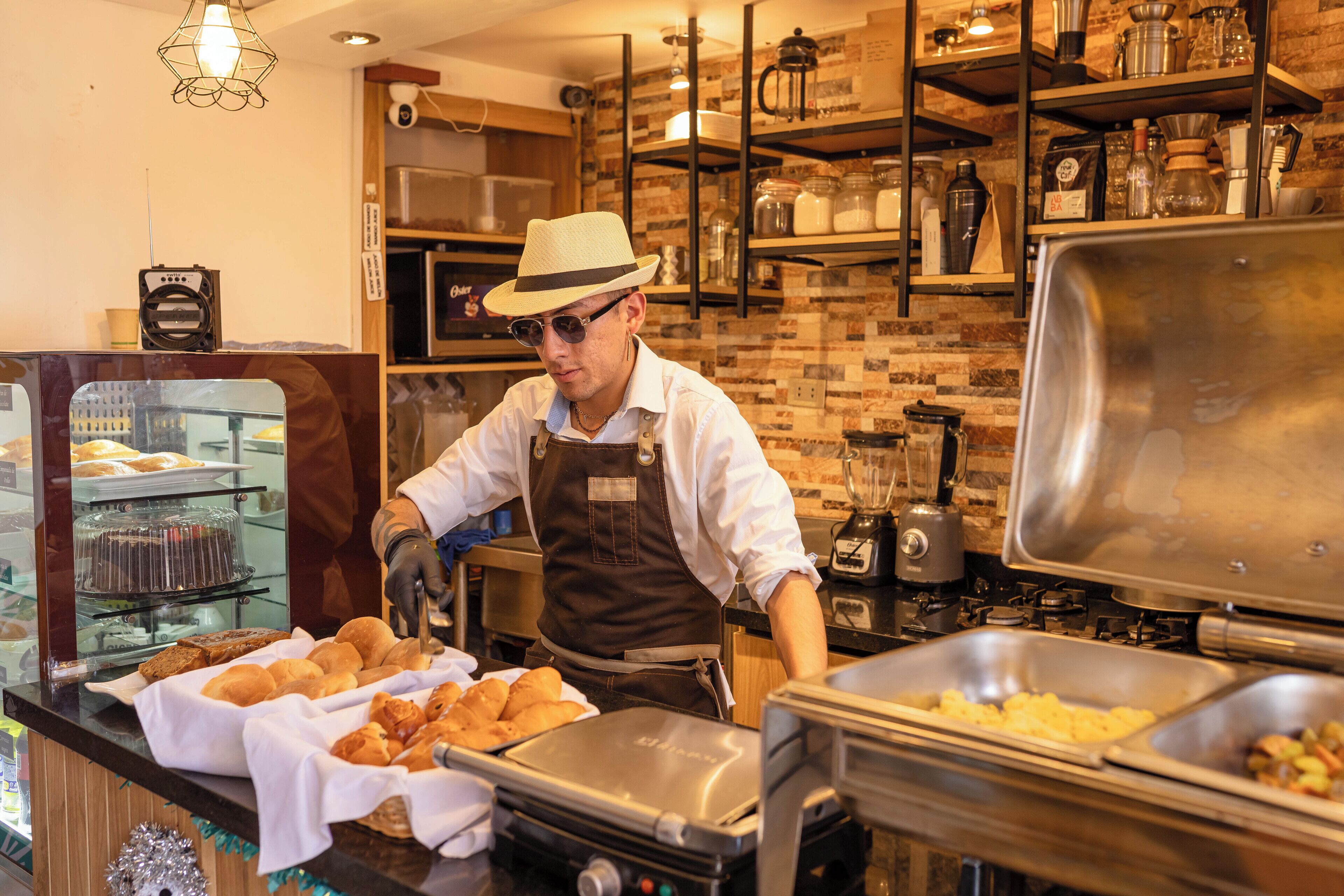 A buffet setup with various food items, a coffee machine, and a person serving food.